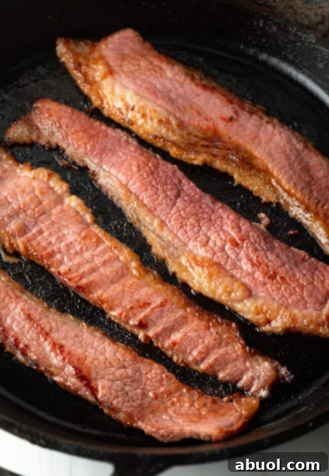 Close view of bacon cooking in a skillet.