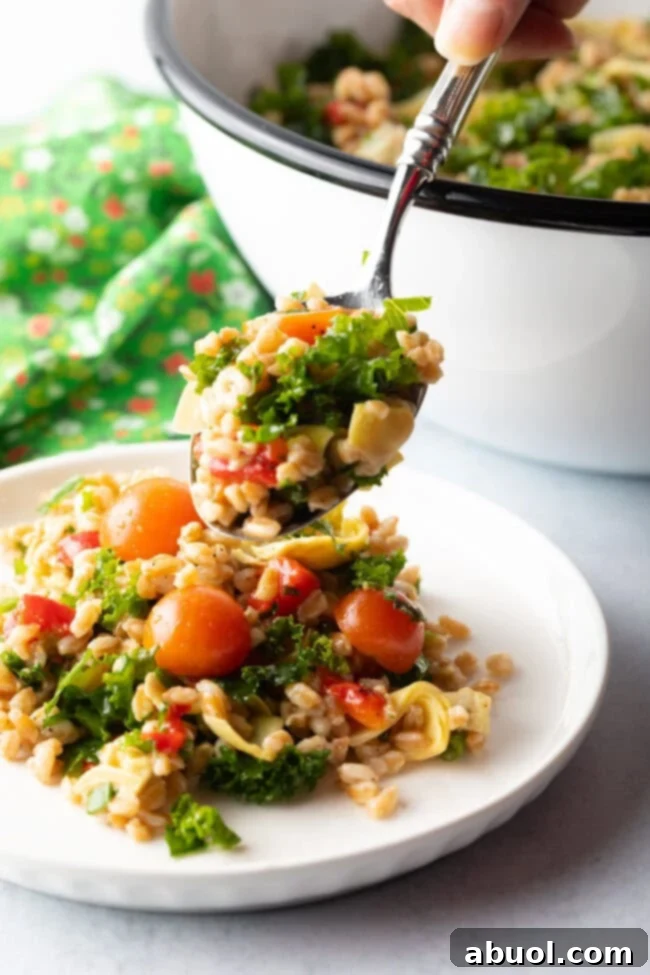 Hand holding spoonful of grain Farro and kale salad to camera.
