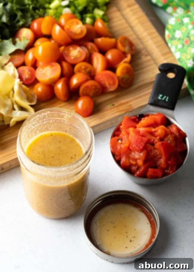 Glass jar with mixed dressing next to 1/2 cup measuring cup with chopped red peppers.