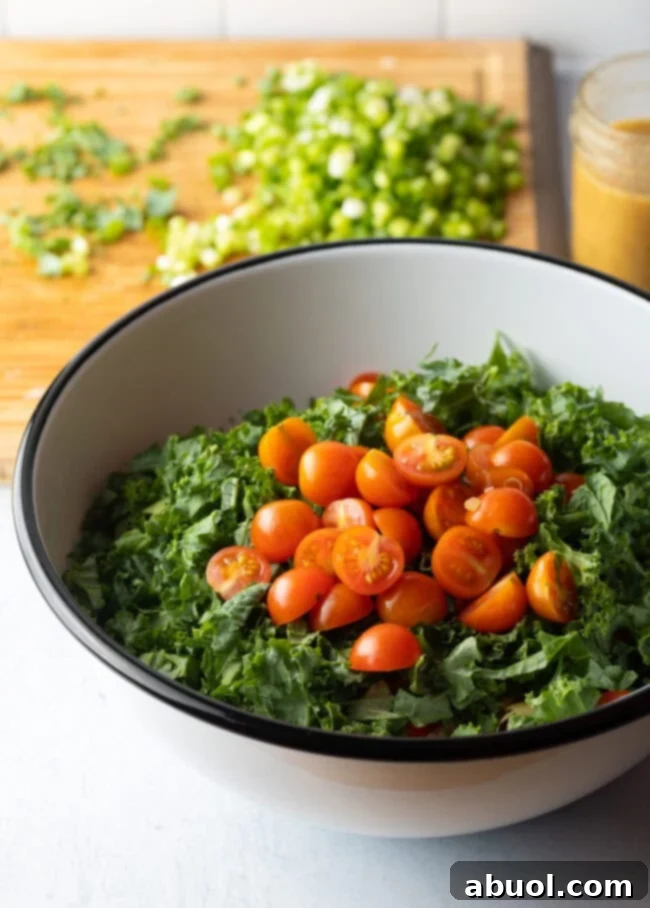 Adding chopped kale and cherry tomatoes to the bowl.