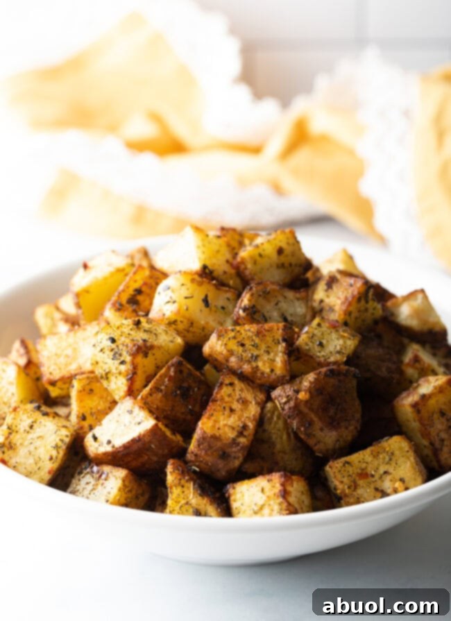 Cubes of roasted seasoned russet potato in a white bowl.