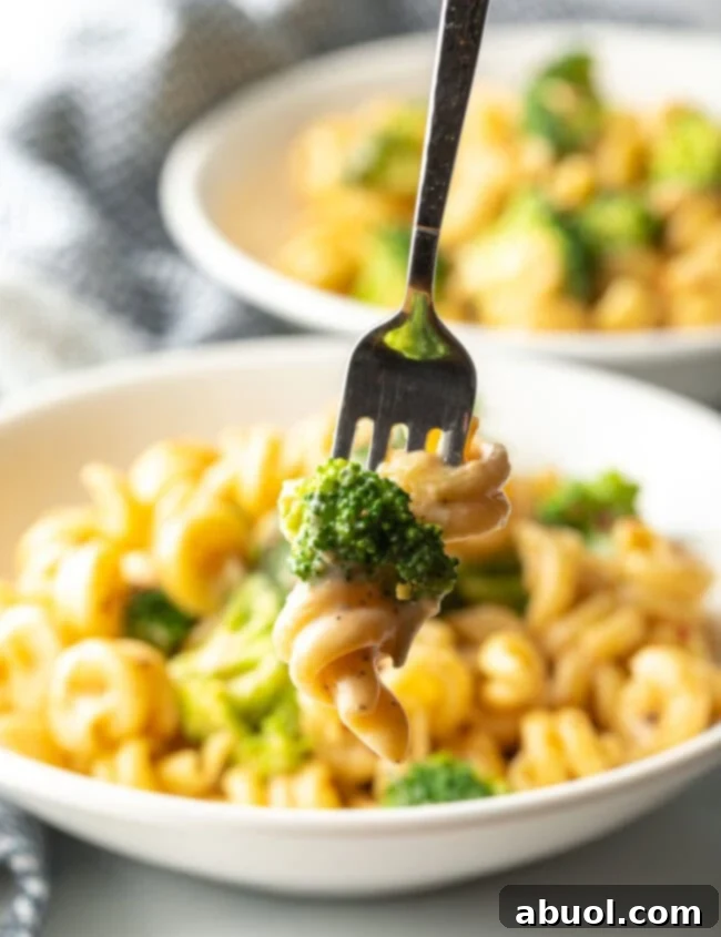 Perfectly Creamy Broccoli Pasta 10 Fork with bite of boiled broccoli and cheese sauce with noodles.