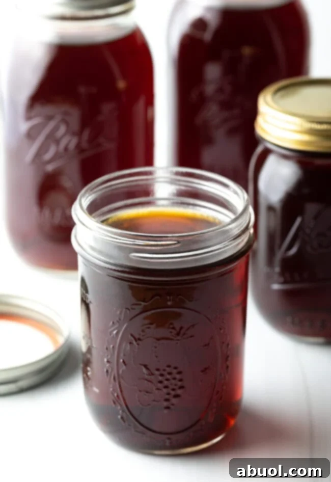 A glass jar filled with beef consomme with more jars in the background.