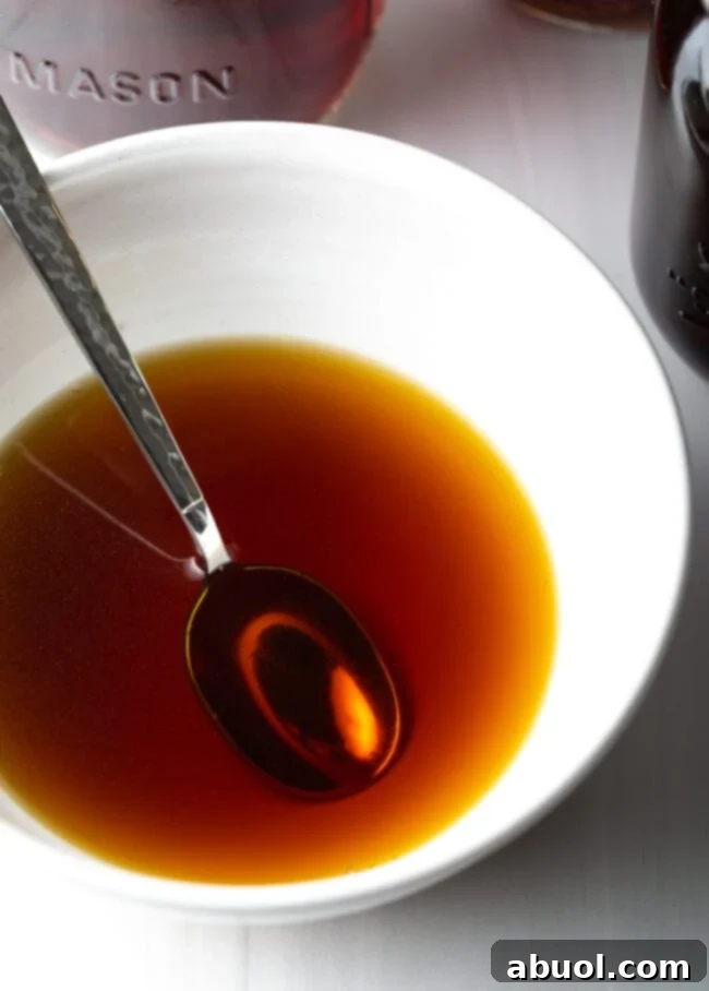 Metal spoon in a white bowl with homemade beef consommé.