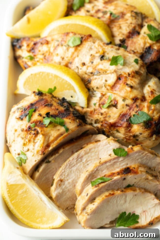Close-up view of perfectly marinated and grilled Greek chicken pieces, garnished with fresh lemon.