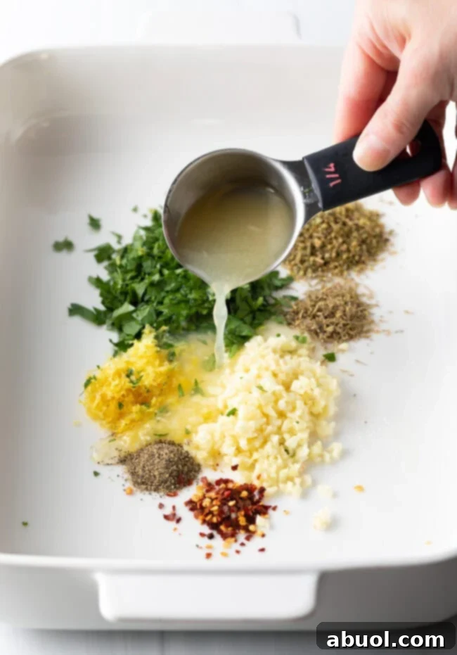 Fresh lemon juice being poured into a dish containing aromatic spices and herbs, starting the marinade mixture.