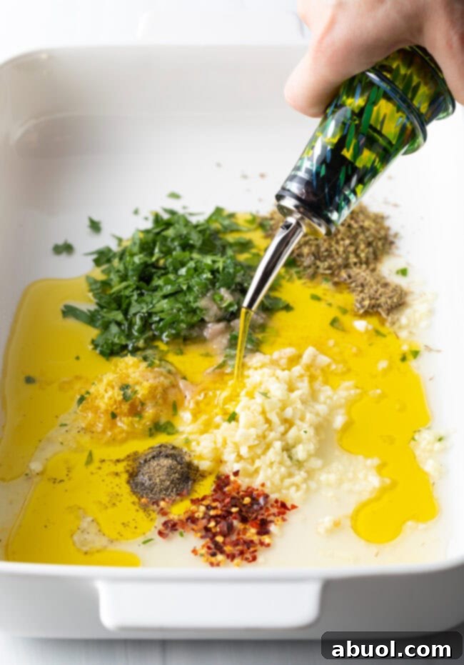 High-quality olive oil being added to the baking dish, complementing the spices and lemon juice for the marinade.