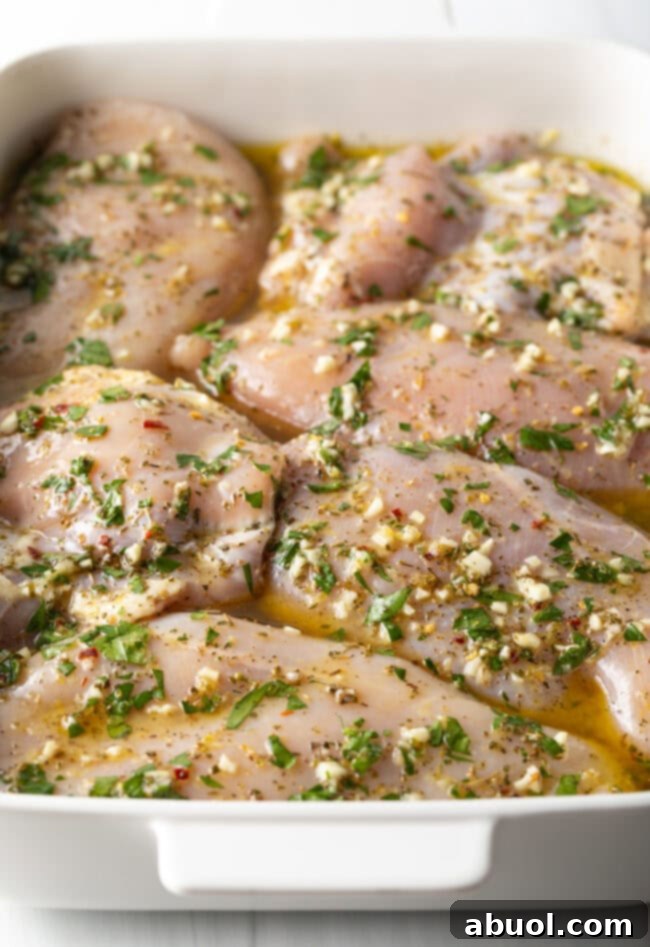 Raw chicken breasts and thighs generously coated in the homemade Greek marinade, ready for refrigeration.