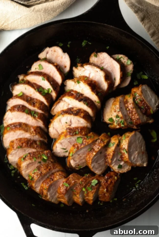 A top-down view of glistening slices of honey garlic pork tenderloin arranged artfully in a black cast iron pan, ready to serve.