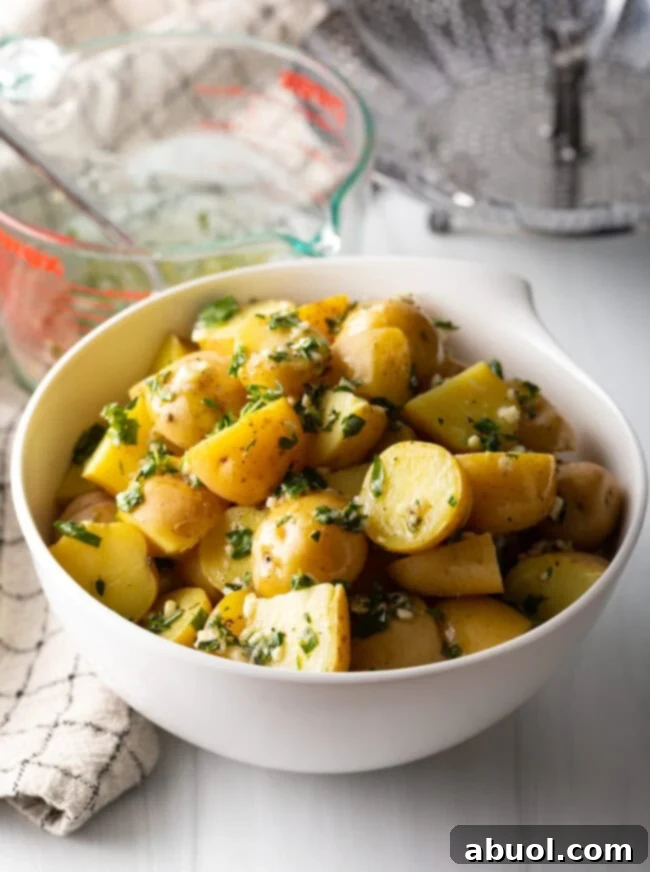 Bowl of steamed baby potatoes tossed with garlic herb butter.