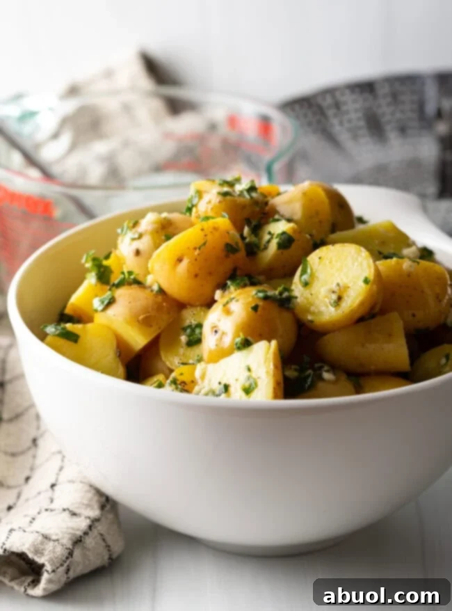 Side view bowl of steamed potatoes with garlic herb butter.
