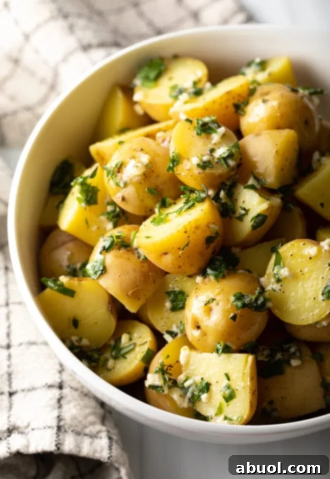 Top down view of bowl with steamed baby potatoes tossed in garlic herb butter.