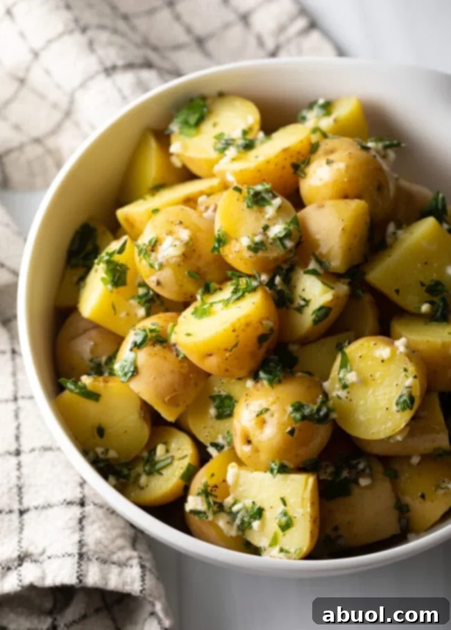 Top down view bowl of steamed baby potatoes tossed with butter garlic herb sauce.