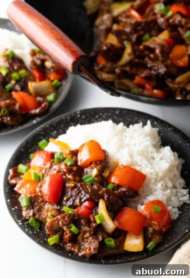 Sweet and Crispy Panda Express Beijing Beef 12 A side view of Beijing Beef served in a black bowl with white rice, showcasing the glistening sauce and crispy texture.