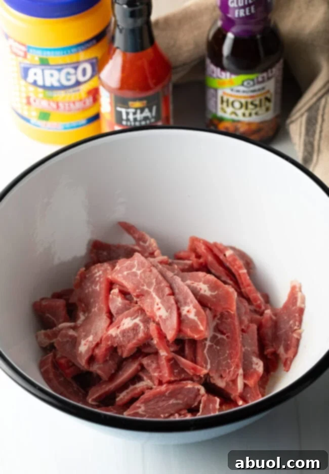 Sweet and Crispy Panda Express Beijing Beef 6 Thinly sliced beef strips coated in egg and cornstarch in a white mixing bowl, ready for frying.
