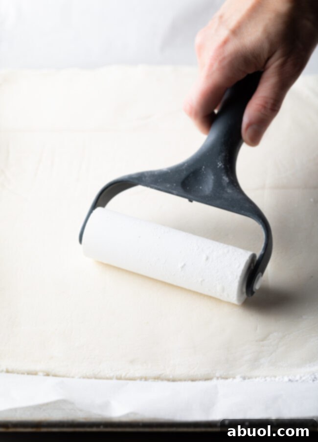 Hand with roller flattening out sheet of mashed potato mixture.