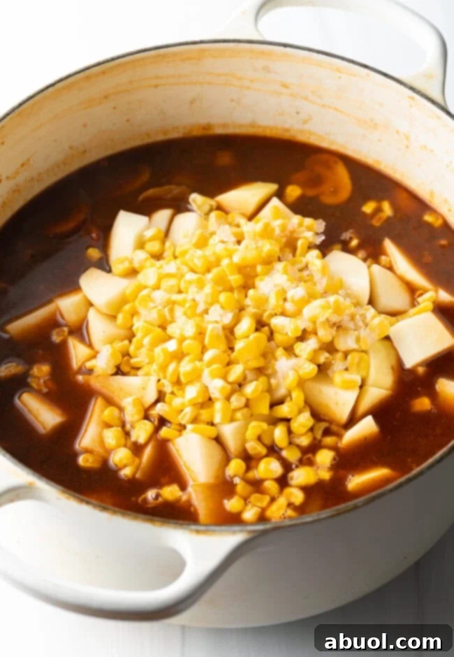 Adding potatoes and garlic in a tomato broth in a pot for hobo stew