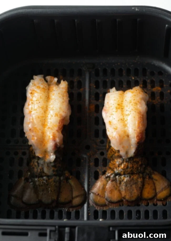 Two raw lobster tails in an air fryer.