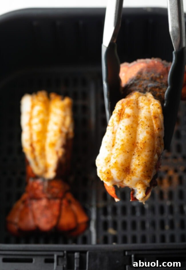 Cooking tongs holding up a cooked tail to camera.