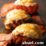 Three plump cooked lobster tails on a baking sheet.