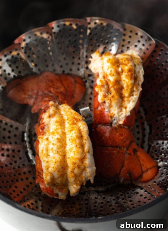 Two cooked lobster tails in a steaming basket