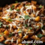 Ground beef and potatoes, topped with shredded parmesan cheese in a skillet.