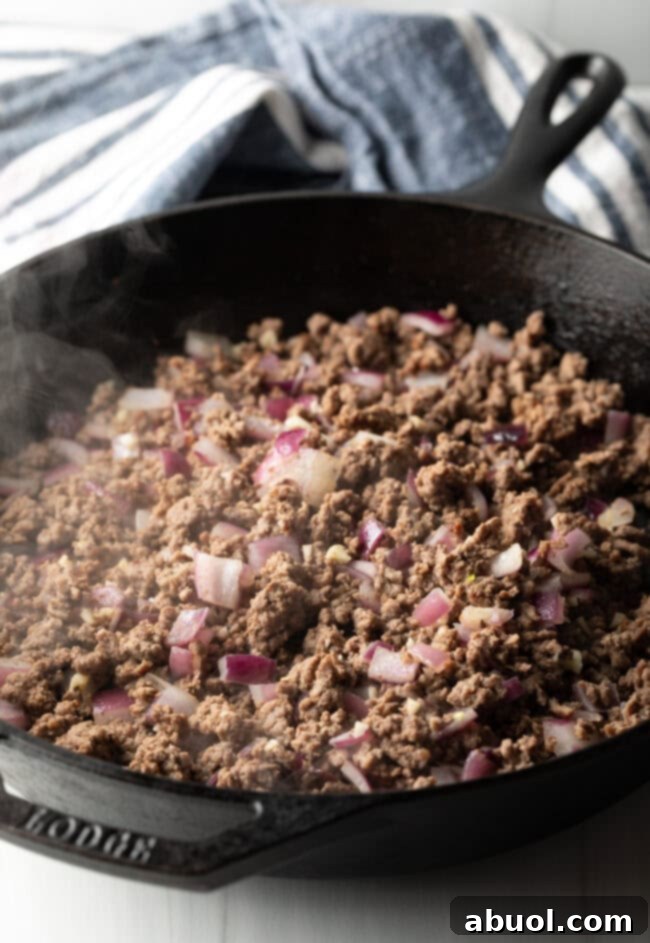 Meat and onions cooking in a skillet.