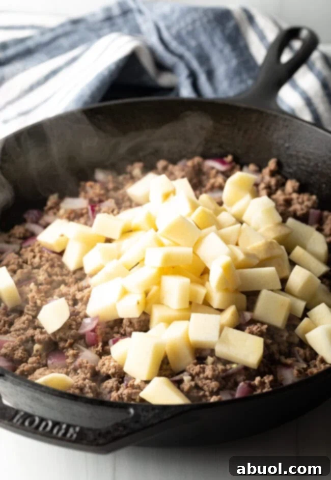 Adding chopped potatoes to the skillet.