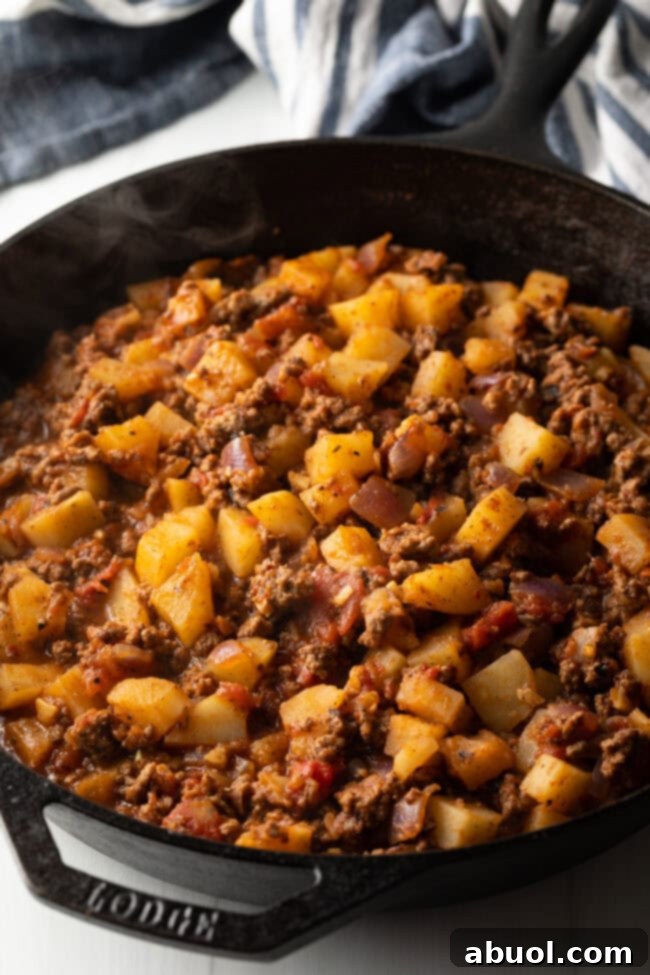 Skillet with cooked ground meat and potato cubes.