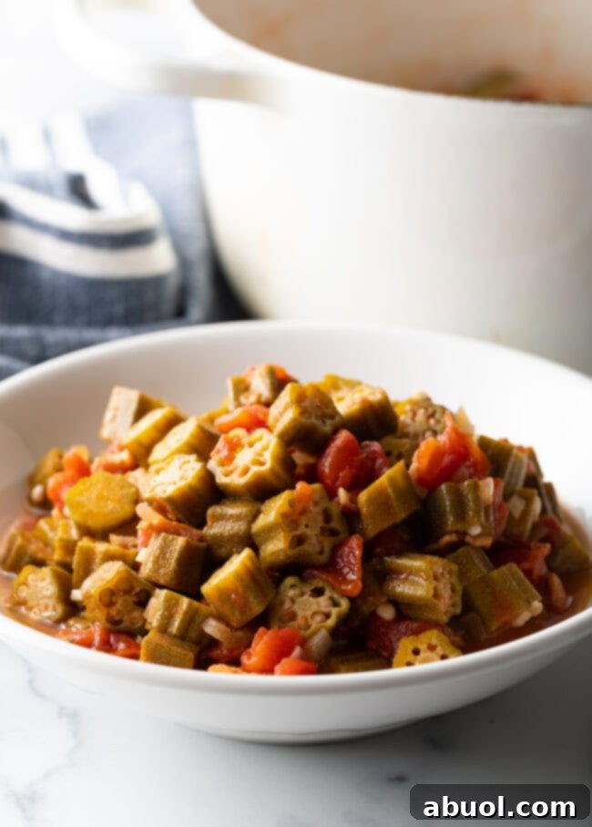A beautifully composed shot of a white bowl filled with the comforting stewed okra and tomatoes, ready to be enjoyed.