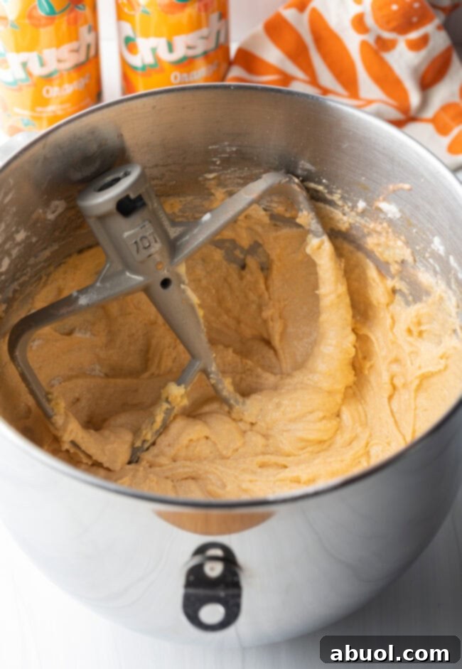 Blended cake batter with metal mixing paddle in metal mixing bowl.