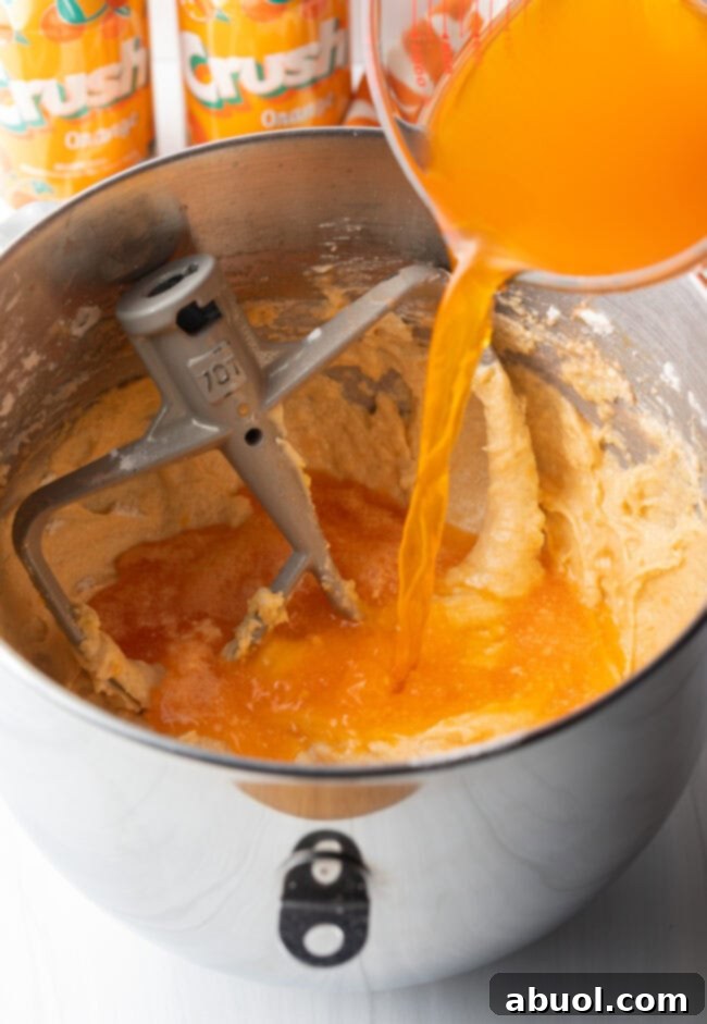Pouring orange crush soda into cake batter.