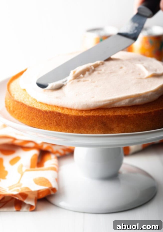 Using cake spatula to add frosting to bottom layer of cake.