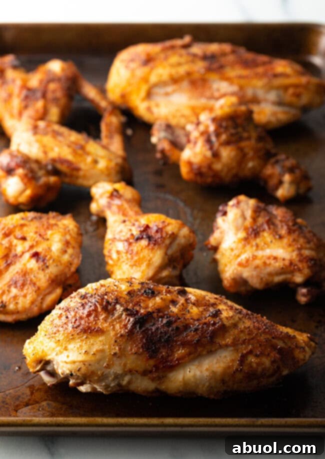 Cooked poultry pieces on a cutting board. Smoked chicken breast with skin on in the foreground.