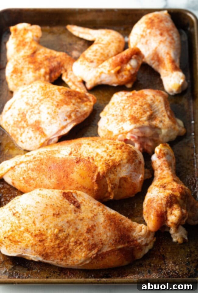 Raw chicken pieces with spices on a cutting board.