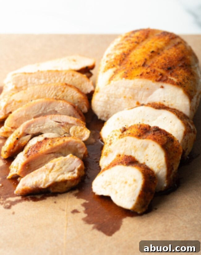 Close view of a smoked chicken breast and a chicken thigh on cutting board. Chicken breast is sliced into 4 large pieces. Thigh is sliced into 7 pieces.