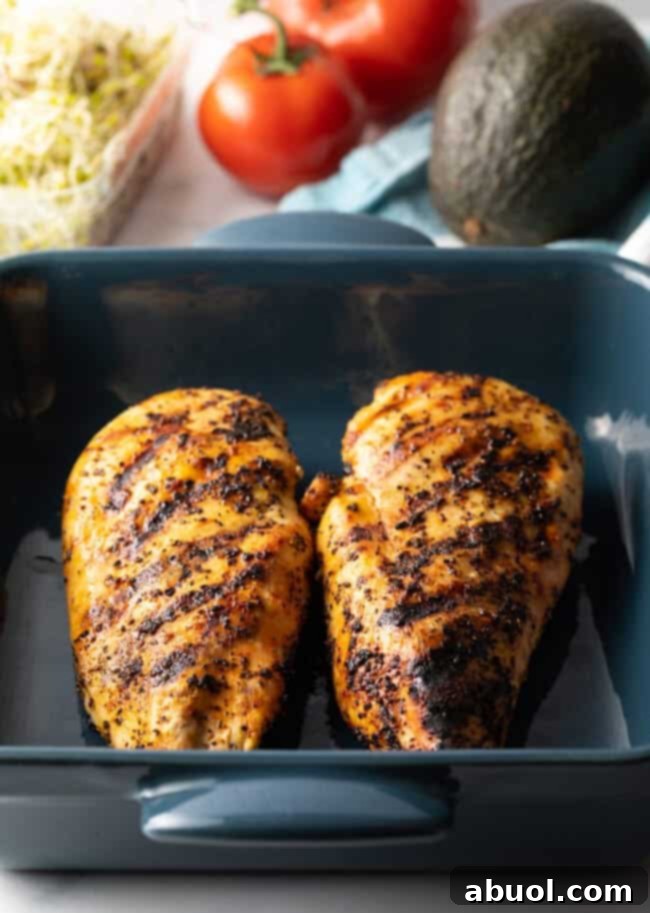 Two large grilled chicken breasts in a blue square baking dish.