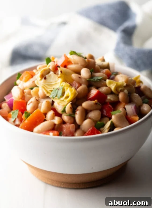 Vibrant Artichoke White Bean Delight 2 White bowl brimming with white bean and artichoke salad, showcasing its vibrant colors and fresh ingredients.