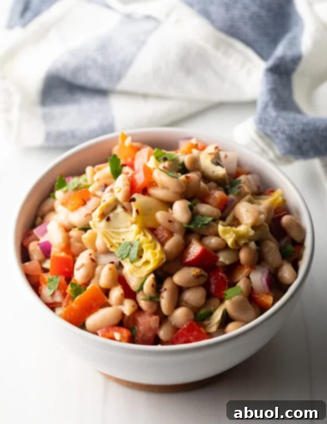 Vibrant Artichoke White Bean Delight 11 White bowl brimming with Artichoke White Bean Salad, beautifully presented and inviting.