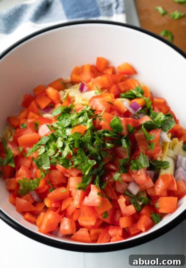 Vibrant Artichoke White Bean Delight 6 Diced tomatoes and fresh herbs nestled in a bowl, waiting for the dressing.