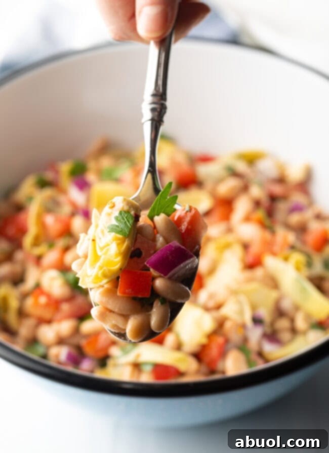 Vibrant Artichoke White Bean Delight 9 Metal spoon showing a generous spoonful of the Artichoke White Bean Salad, highlighting its chunky texture and colorful ingredients.