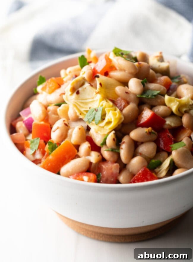 Vibrant Artichoke White Bean Delight 10 White bowl brimming with Artichoke White Bean Salad, glistening with dressing and vibrant colors.