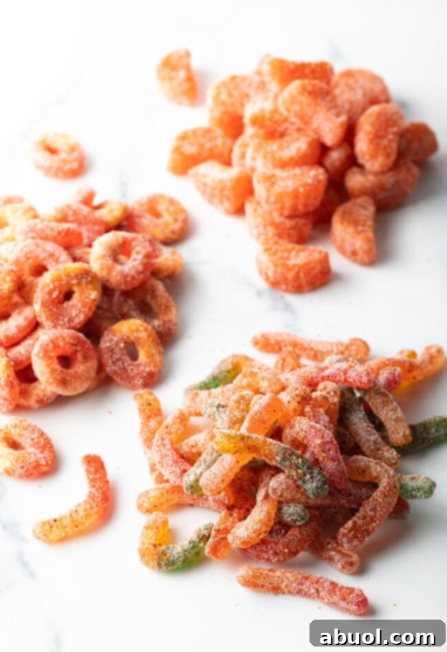 Top down view of four piles of gummy candies, each now coated with chamoy and tajin seasoning.
