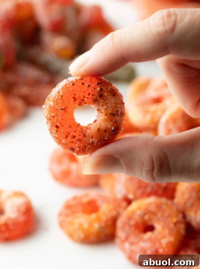 Hand holding a seasoned Mexican Chamoy Candy (dulces enchilados) ring to camera.