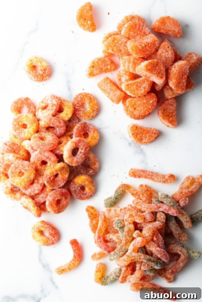 Top down view of four piles of dulces enchilados gummy candies, each now coated with chamoy and tajin seasoning.