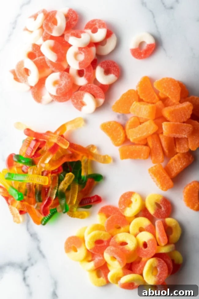 Top down view of four piles of different gummy candies: White and orange circles, orange slices, yellow and orange circles.
