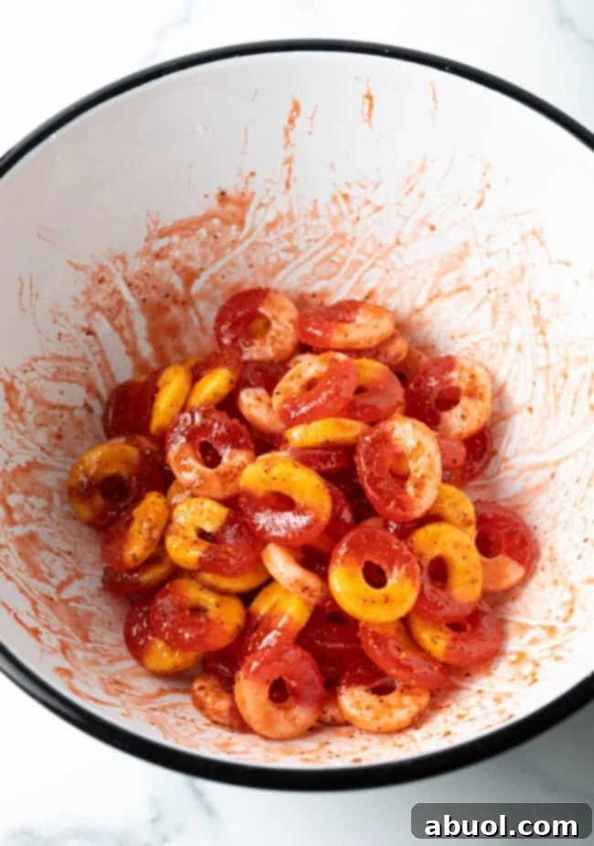 Gummy fruit rings tossed in sauce and seasoning in a white bowl.