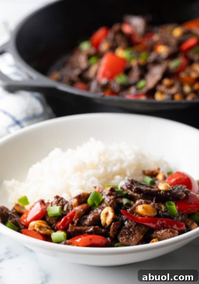 Kung Pao Beef stir-fry, rich with tender beef, red bell peppers, and scallions, cooked to perfection in a cast iron skillet.