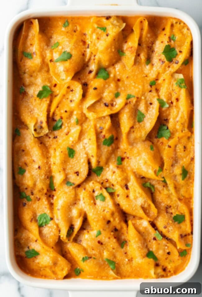 Top-down view of baked stuffed shells seafood pasta in a baking dish, garnished with fresh herbs.