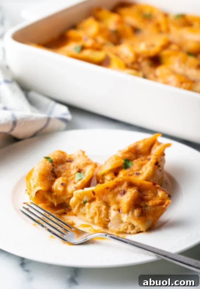A close-up of a serving of cheesy seafood pasta on a white plate with a fork, ready to be enjoyed.